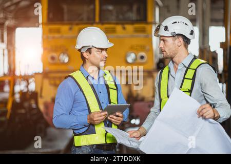 Engineer team smart young skill worker consulting supervisor working together with design floor plan in locomotive train depot workshop Stock Photo
