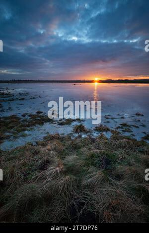 Cloudy evening sky with sunset over a wet meadow Stock Photo