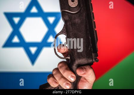 Israel vs Palestine war concept. Man holds a gun. Flags on background. Stock Photo
