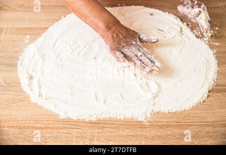 Dough on white powder covered table. Hand flour. Hands baker with flour in kitchen. Hands woman covered in flours Stock Photo