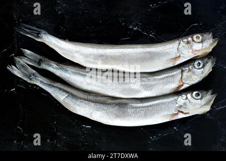 Three Frozen Chapelin Shisamo Japanese Fish on Black Stone Plate Stock Photo