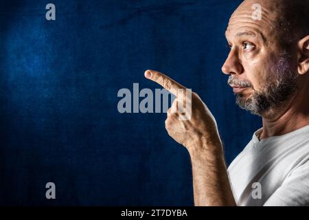 Man, confused, pointing to the side. Sad people. against blue background. Stock Photo