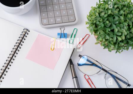 Office desk with pink sticker on notebook. Stock Photo
