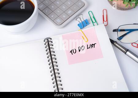Office desk with pink sticker on notebook. Stock Photo
