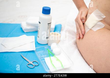 Close up view of hand touching wound with gauze on hip and Aid Kit utensils Stock Photo