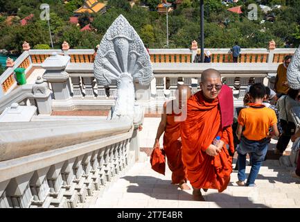 Two buddhist monks climb steps past visitors at Oudong Temple in Kandal Province near Phnom Penh, Cambodia. Stock Photo