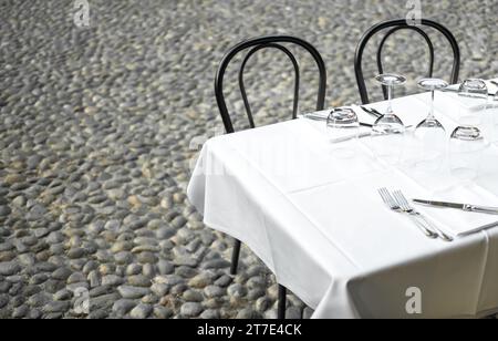 Elegant Restaurant table in terrace and rustic grey stone street background Stock Photo