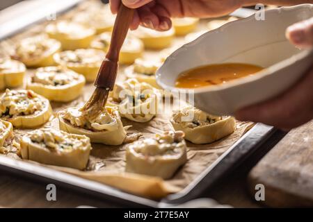 The cook brushes an egg onto a puff pastry roll. Recipe procedure: 9 of 10 Stock Photo