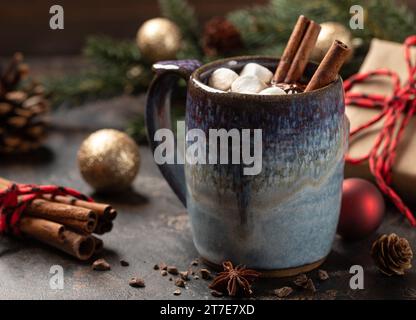 Cup of hot chocolate with marshmallows, cinnamon and anise.  Holiday decorations in background Stock Photo