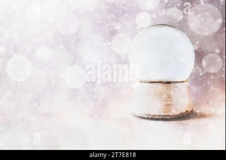 Rustic empty snow globe over a textured background with falling snow and streams of light and glitter. Copy space available. Stock Photo