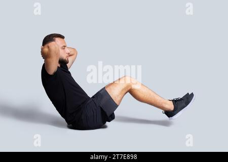 Focused strong young european guy with beard in sportswear make exercises for abs Stock Photo