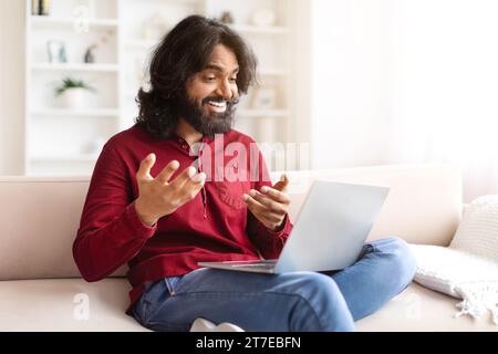 Positive indian guy have video call with friend, using laptop Stock Photo