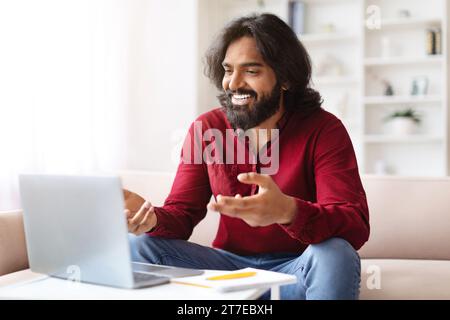 Positive indian guy have video call with colleagues, using laptop Stock Photo