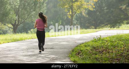 A Woman Embracing Freedom and Serenity as She Runs Through a Scenic Park Path Stock Photo
