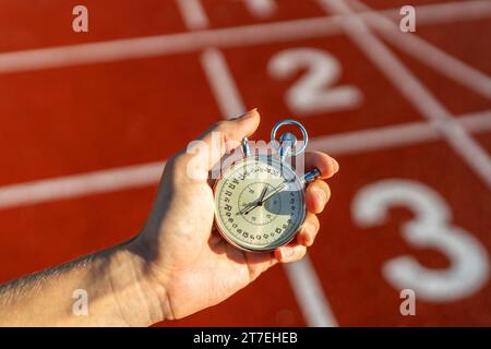 Stopwatch in hand, track numbers background, timing, sports, competition, measuring performance Stock Photo
