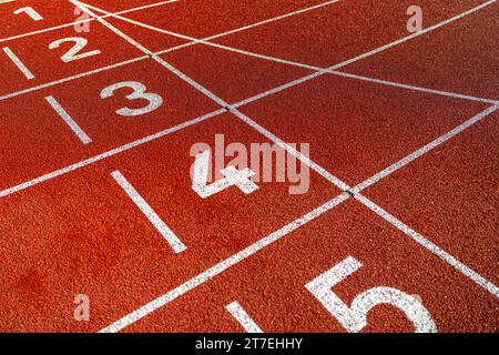 Close-up of lane numbers on a red running track, textured surface, no people Stock Photo