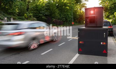 Mobile speed camera on city road with passing cars in motion blur, trees in background Stock Photo