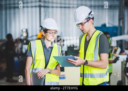Engineers mechanic team holding check list on clipboard and pen in steel factory workshop. Industry robot programming software for automated manufactu Stock Photo