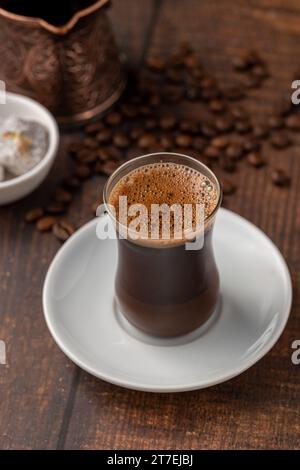 Turkish coffee in glass tea cup with Turkish delight on wooden table Stock Photo