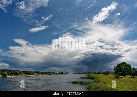 View along the German-Polish border river Oder to a big thunderstorm front, from which partly rain falls, sunny weather - Location: Germany Poland bor Stock Photo