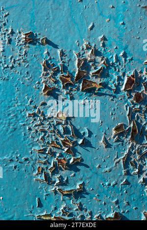 Blue peeling paint on the wall. Old concrete wall with cracked flaking paint. Weathered rough painted surface with patterns of cracks and peeling. Hig Stock Photo