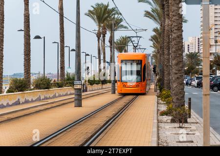 Alicante, Spain - October 14, 2023: Orange streetcar running along the promenade between Alicante and San Juan Stock Photo