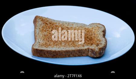 A single slice of wholemeal toast, unbuttered, on a white plate. Stock Photo