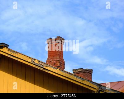 Old brick chimney in need of repair on a roof. Heating and fire safety concept Stock Photo