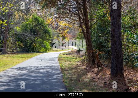 Two distant bicyclists ride on a paved trail through an autumn scene of changing leaves. Stock Photo