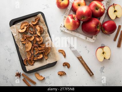 Brown dried apple slices on baking tray with red ripe apples. Stock Photo