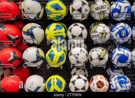 Italy - November 15, 2023: soccer balls of various colors and brands displayed on shelves for sale in Decathlon clothing and sporting goods store, Dec Stock Photo
