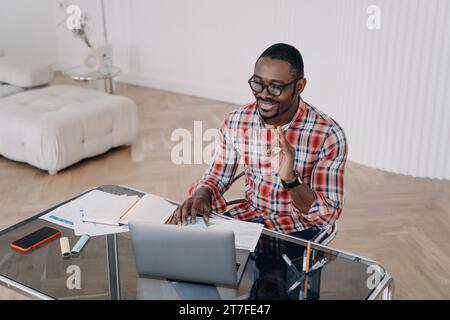 Man in checkered shirt at desk, gesturing during a cheerful video call Stock Photo