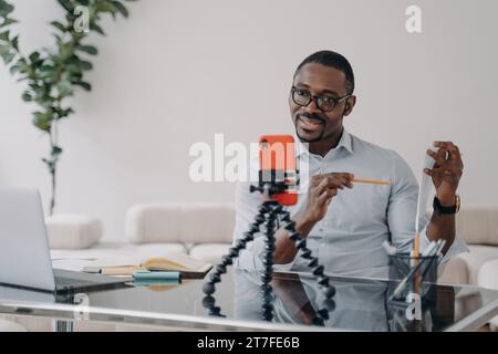 Man recording a vlog with smartphone on tripod, engaging with audience Stock Photo