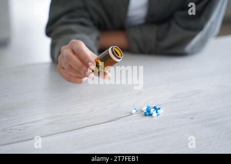 Hand pouring out pills from a bottle, a concept of medication management Stock Photo