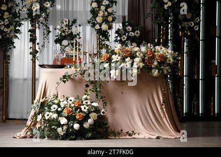 Festive wedding table for the newlyweds, decorated with compositions of fresh flowers and candles. Wedding decorations. Celebration in the banquet Stock Photo