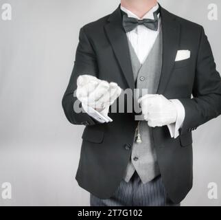 Portrait of Butler or Hotel Concierge in Dark Suit and White Gloves Offering Helping Hand. Service Industry and Professional Hospitality. Stock Photo