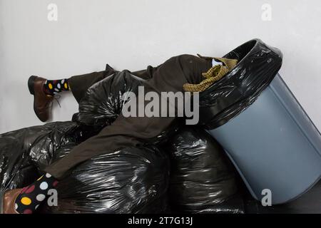 https://l450v.alamy.com/450v/2t7g13j/portrait-of-man-in-ugly-suit-stuck-in-trash-can-atop-pile-of-black-garbage-bags-concept-of-over-a-barrel-out-of-fashion-2t7g13j.jpg