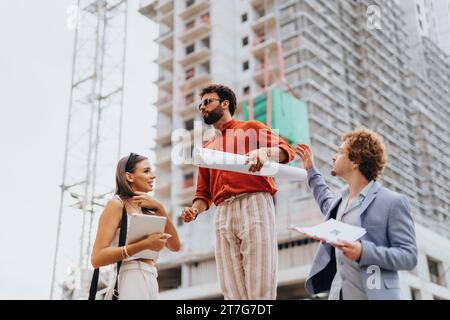 Corporate team analyzing a project blueprint outdoors. Discussing costs, paperwork, and sustainable design. Teamwork for profitable development. Stock Photo