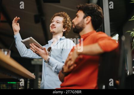 Successful Collaboration: Architects and Engineers Discussing Blueprint at Coffee Bar Stock Photo