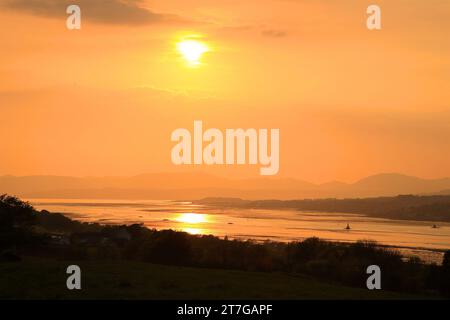 yellow sun with orange sky setting over the river clyde with the hills and mountains in view. Stock Photo