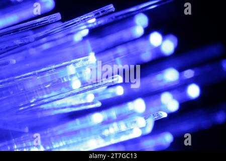 Optical fiber strands transmitting blue light in darkness, macro view Stock Photo
