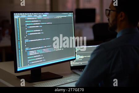 Busy businessman software developer working on pc computer in dark night office. Stock Photo