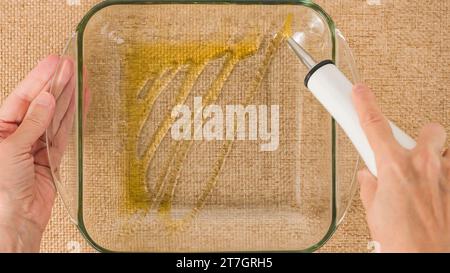 Chef hands pouring olive oil into a glass baking dish. Close-up view from above, baking process Stock Photo
