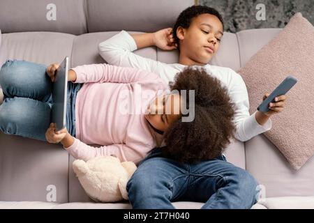 Siblings using tablet mobile home 2 Stock Photo