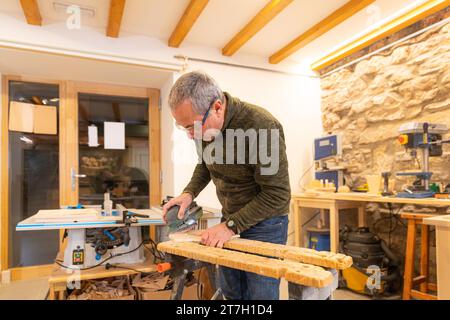 Carpenter using an electric tool to sanding a piece of wood in a workshop alone Stock Photo