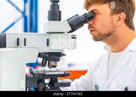 Close-up of a concentrated biologist using microscope during research in laboratory Stock Photo