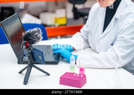 Scientists using mobile to recording while talking next to samples and using laptop in a research laboratory Stock Photo