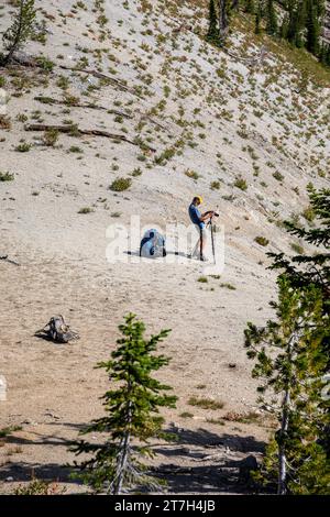 OR02764-00...OREGON - Tall photographer with a short tripod composing a picture along the Bowman Trail in the Eagle Cap Wilderness. Stock Photo
