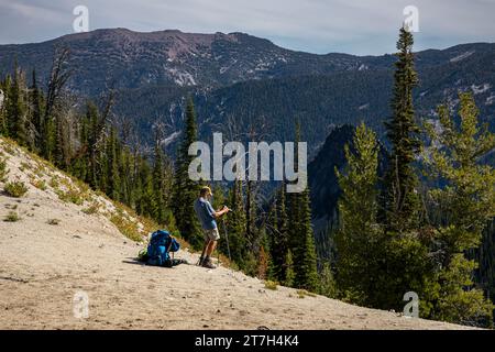 OR02765-00...OREGON - Tall photographer with a short tripod composing a picture along the Bowman Trail in the Eagle Cap Wilderness. Stock Photo