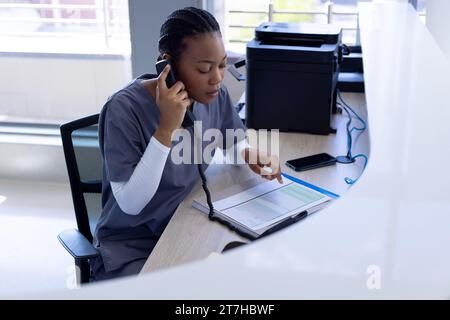 African american female doctor talking on phone in hospital reception Stock Photo